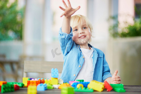 幼儿园内部摄影照片_小男孩玩彩色塑料建筑积木