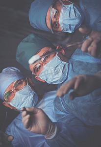 在手术室工作的一组外科医生用蓝色调.执行业务的医疗小组