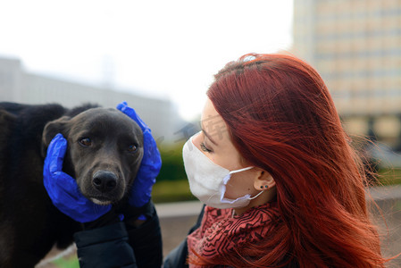 年轻的女性使用面罩作为防止与她的狗一起散步的验尸官。全球COVID-19大流行病概念图像.