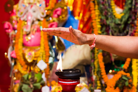 一只手拿着火焰作为祝福从一盏点燃的粘土灯上的粘土立场或崇拜偶像 durgapuja 印度排灯节