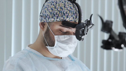 戴口罩和外科眼镜的外科医生做手术。行动。专业外科医生在手术过程中的面部特写。配备最新医疗技术的外科医生