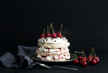 Pavlova cake with fresh cherry, cheese cream and chocolate chips in vintage silver plate over dark grunge background