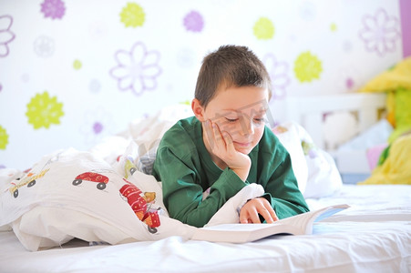 读本书摄影照片_小男孩在他的床上读一本书