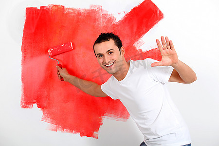 改革红色摄影照片_一位年轻人把房子的墙壁漆成红色