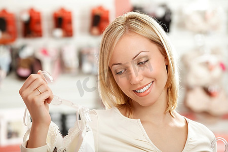 零售购物摄影照片_这位女士看着商店里的胸罩，微笑着