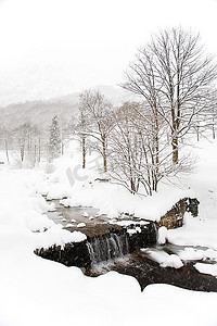 风景摄影照片_冬季风景：山区河流在雪地里。