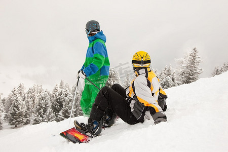 滑雪者和单板滑雪运动员坐在雪地里眺望高山冬季的风景