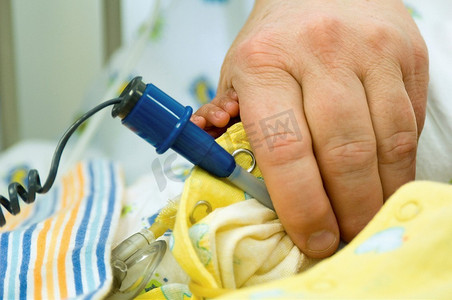手体温计摄影照片_使用婴儿体温计的新生儿护士。