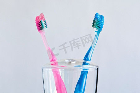 对立面摄影照片_牙刷架里有几把粉色和蓝色的牙刷。