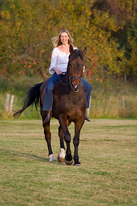 一位迷人的年轻女子在秋天骑马，背景是一片苹果园