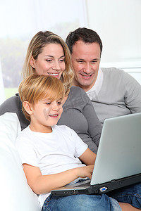 爸爸拿摄影照片_父母和小男孩在家里拿着笔记本电脑