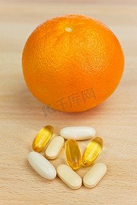 一个橙子和药片，要么是药丸，要么是营养维生素补充剂。