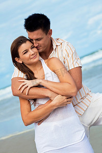 一对年轻的男女在蔚蓝的海滩上像浪漫情侣一样拥抱在一起
