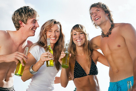 四个非常漂亮的人在海滩上庆祝他们生命中的夏天的火辣派对-专注于面孔