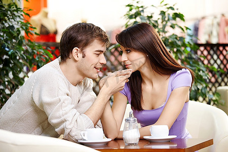 年轻男子在咖啡馆里向美丽的女孩吻手