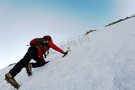 冰雪摄影照片_欧洲意大利阿尔卑斯山，一名登山者在冰雪覆盖的斜坡上攀登陡峭的路线。