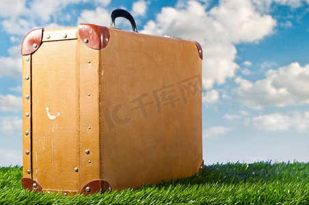 假期旅行行李箱摄影照片_草地上的旧行李箱，旅行的概念