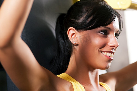 健身房里非常健康和美丽的年轻女子在健身器上锻炼和举重