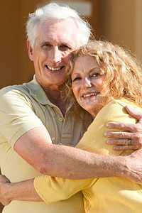 一对老年退休男女拥抱在一起，幸福地在一起。