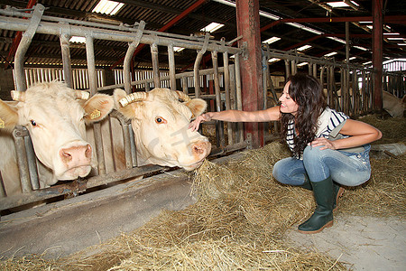 微笑的女农民抚摸奶牛