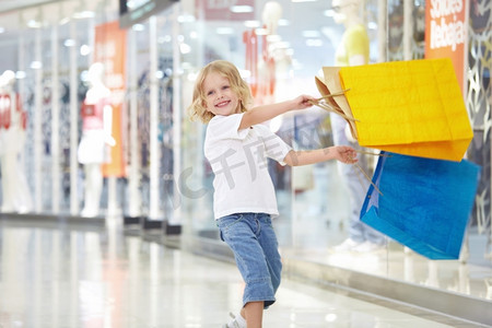 零售购物摄影照片_一个在商店里拿着包裹的小女孩