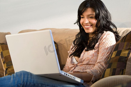 一位年轻漂亮的西班牙裔女士正在使用她的笔记本电脑