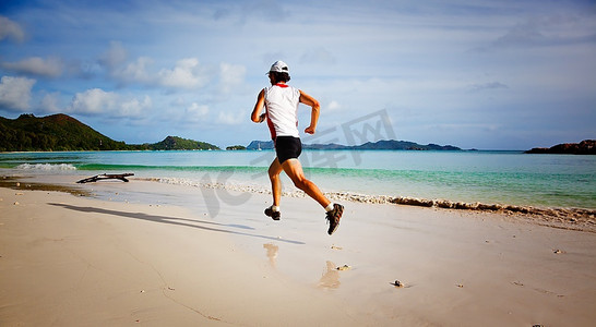 印度洋摄影照片_一个年轻人在日出时分在热带空旷的海滩上奔跑；塞舌尔，印度洋