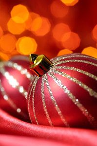 红色丝绸上的圣诞装饰球在背景模糊灯光的映衬下