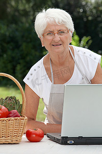 花园里的老年妇女拿着一篮子新鲜蔬菜的特写