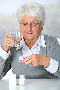 药丸药瓶摄影照片_老妇人看药瓶的特写