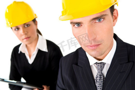 一张选择性聚焦的工业概念照片，展示了一对戴着安全帽的男人和女人。焦点放在前景中的那个人身上
