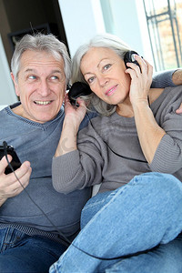 一对高年级夫妇戴着耳机听音乐