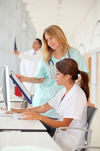 带实习生的护士在电脑前工作