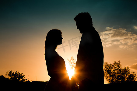 相互促进摄影照片_一对相爱的情侣在夏天的夕阳下相互抚摸着背光