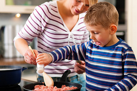 全家人在厨房里做饭--母亲在做意大利面酱，儿子在里面放盐