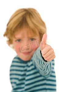 一个年轻的金发男孩对着镜头竖起大拇指，焦点在他的手上。
