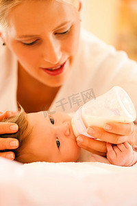 母亲正在用奶瓶喂婴儿，场面非常宁静
