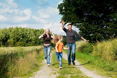 快乐的家庭(妈妈、爸爸和孩子)在大自然中散步，玩捉迷藏