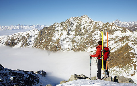 男子滑雪登山者在他攀登的顶端；水平体型。意大利阿尔卑斯山。