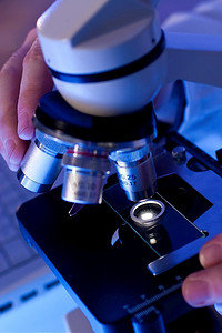 使用显微镜和笔记本电脑的医学或科学研究人员