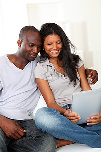 幸福恩爱的夫妻坐在沙发上看着电子平板电脑