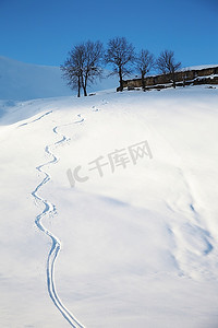 有滑雪痕迹的雪地；背景是意大利的一个高山农场。