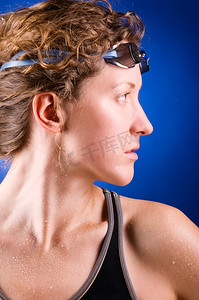 漂亮的女游泳者在蓝色的背景上斜视