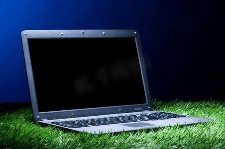 草地上的现代笔记本电脑在黑暗中照亮
