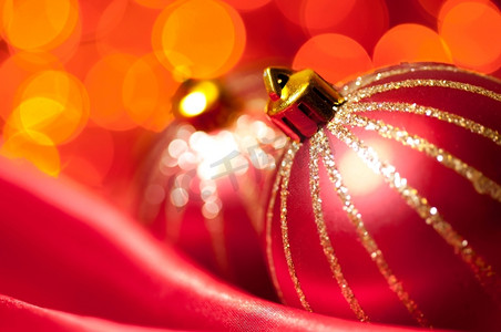 红色丝绸上的圣诞装饰球与背景模糊的灯光映衬，浅浅的DOF