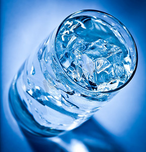 深蓝色背景上的一杯加冰的水