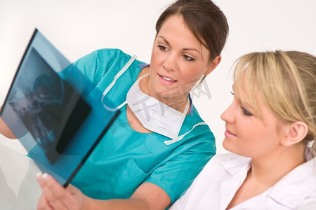 一名女医生和她的护理同事在检查人类头骨的X光。