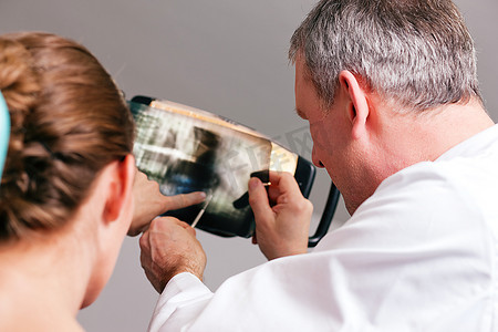 牙医向他的病人解释X光照片的细节，专注于医生的眼睛