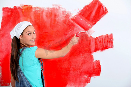 改革红色摄影照片_一名年轻女子把房子的墙壁漆成红色