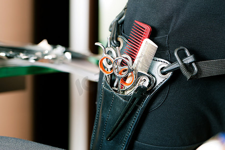 平板皮套摄影照片_剪刀袋或理发师皮套的特写，戴在臀部，有很多工具